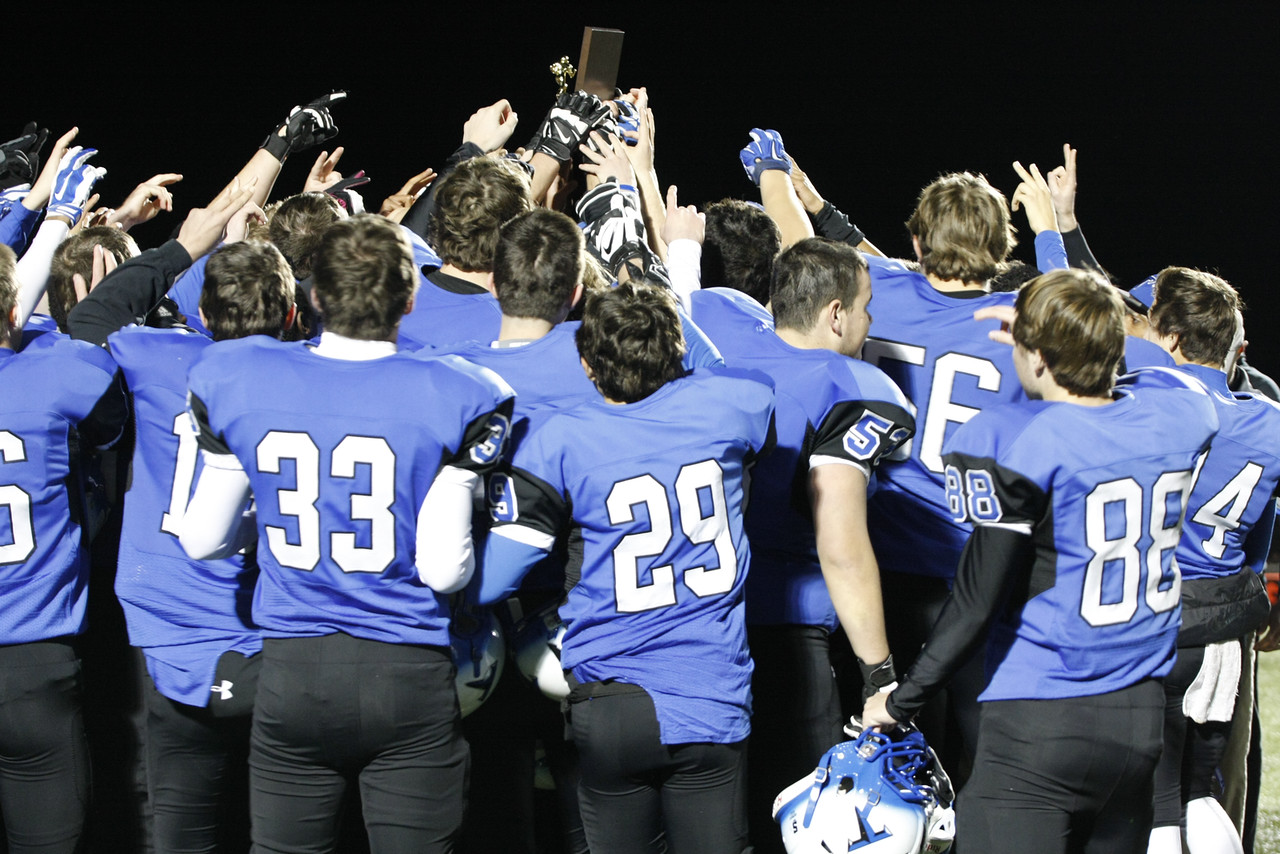 The varsity football Huskies celebrate their win against Briar Woods High School  last Friday, November 7th, as they hold up the District Championship plaque in a huddle. Photo Credit: Hanna Duenkel